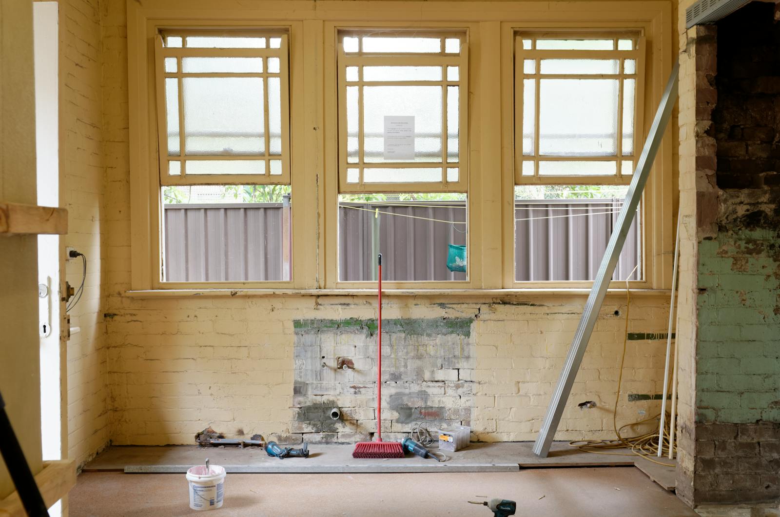 An empty room featuring large windows, ready for renovation in Sydney, Australia.